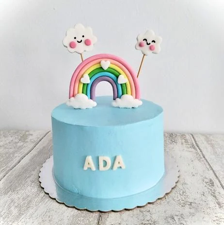 Tarta azul con arcoíris, nubes y flores