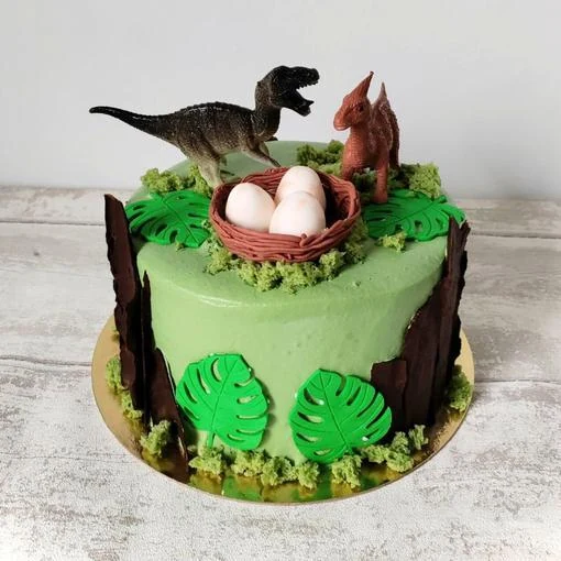 Tarta verde con dinosaurios y huevos en un nido