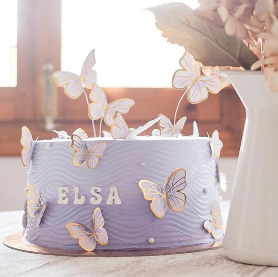 Tarta lila con mariposas blancas y doradas